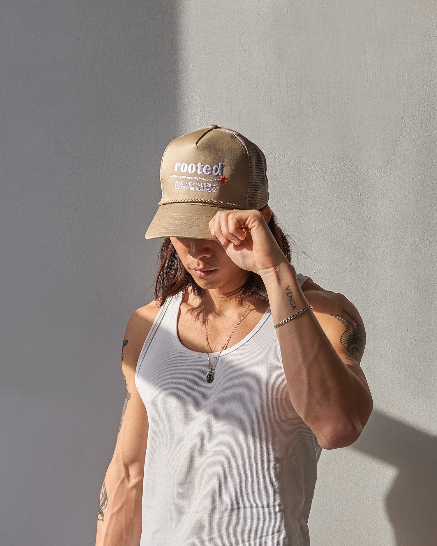 A man wearing the Rooted Plant Club Trucker Hat in khaki.